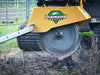 A red Diamond Mowers stump grinder attachment mounted on a tractor is grinding a large tree stump into chips.