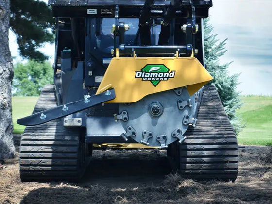 A  Diamond Mowers stump grinder with the words "Diamond Mowers" prominently displayed grinds a tree stump.
