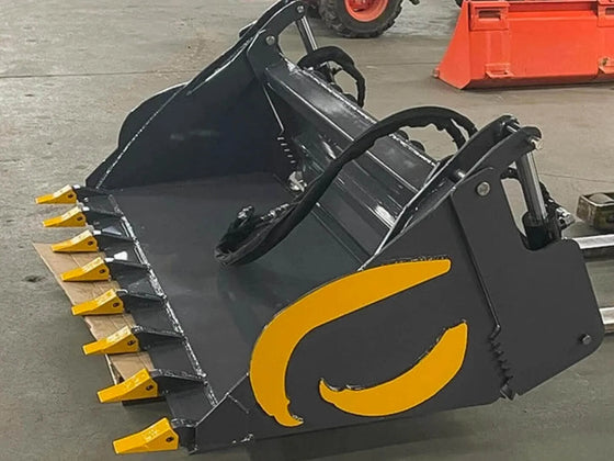 A yellow and gray bucket with the logo "RAPTOR" on it sitting on top of a cardboard box in a garage. The bucket is tilted to the side.