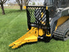 Dominator tree puller: This yellow and black attachment is mounted on a skid steer, which is parked in a grassy field with trees in the background.