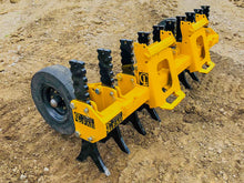  A yellow tracked skid steer loader with black rubber tracks and a yellow plow attachment parked on a dirt construction site. 
