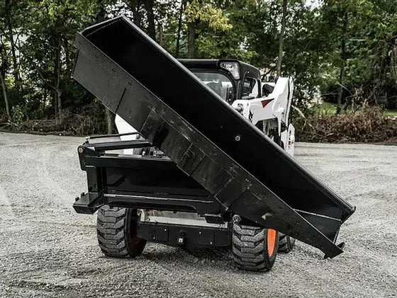 The image shows a large bucket attached to a skid steer loader. The skid steer is parked on a gravel road, and the bucket is tilted to the side. The skid steer is yellow and black, and the bucket is black.
