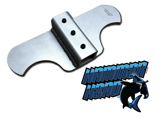 A close-up image of a hammer and shark logo. The hammer is in the foreground and the shark logo is in the background. The hammer is silver and the shark logo is black.