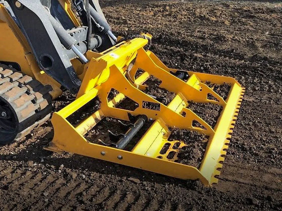 The land leveler is parked on a dirt lot.