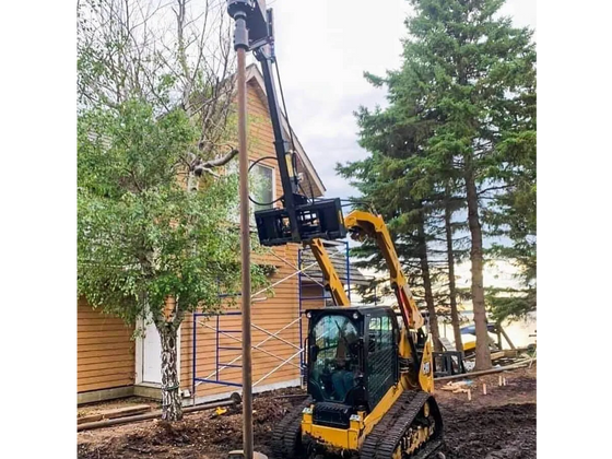 A powerful construction vehicle, a bulldozer with a massive drill attached to its front, bores into the earth in front of a suburban home.
